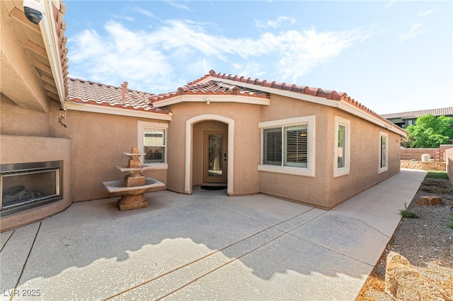 view of front of property featuring a patio, a tile roof, and stucco siding