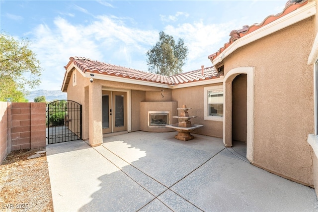 rear view of property with a gate, stucco siding, a tile roof, and fence