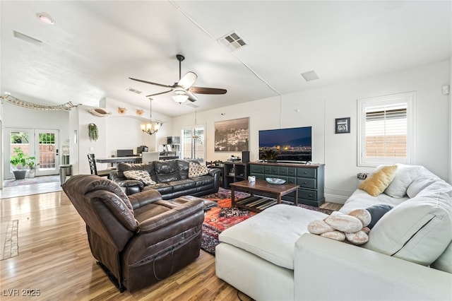 living room with visible vents, light wood finished floors, and ceiling fan with notable chandelier