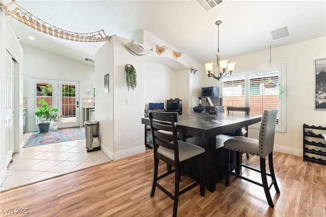 dining area with baseboards, visible vents, an inviting chandelier, and light wood-style flooring