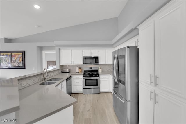 kitchen featuring a sink, vaulted ceiling, stainless steel appliances, and white cabinetry