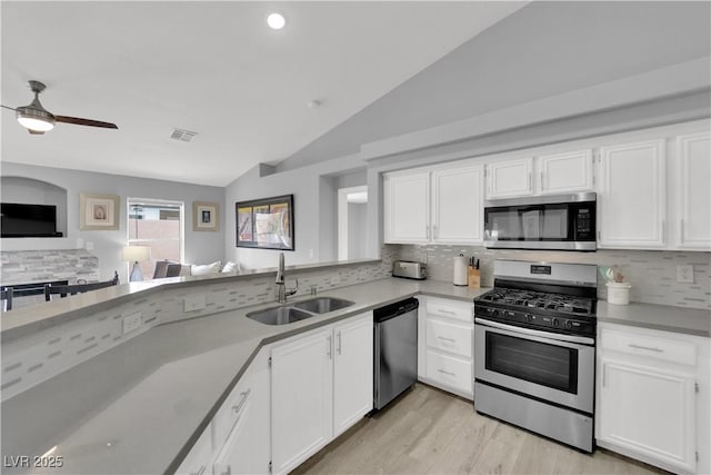 kitchen featuring visible vents, a sink, backsplash, vaulted ceiling, and stainless steel appliances