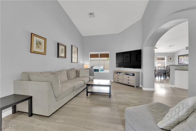 living room featuring a healthy amount of sunlight, high vaulted ceiling, light wood-style floors, and visible vents