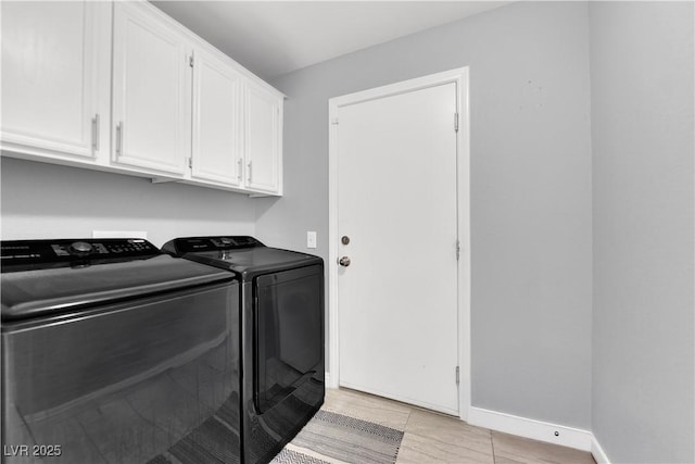 clothes washing area featuring baseboards, washing machine and dryer, and cabinet space