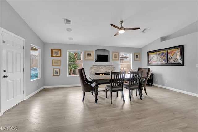 dining area featuring ceiling fan, baseboards, lofted ceiling, light wood-type flooring, and visible vents