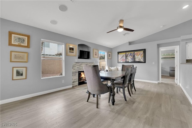dining area with plenty of natural light, a fireplace, ceiling fan, and lofted ceiling