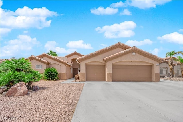 mediterranean / spanish house featuring an attached garage, stucco siding, driveway, and a tile roof
