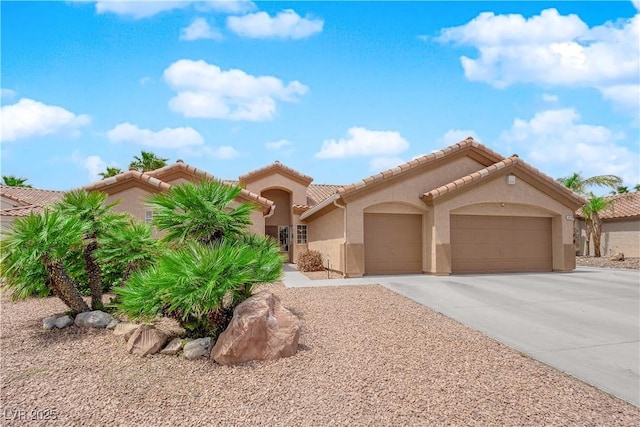 mediterranean / spanish-style house featuring concrete driveway, stucco siding, a tile roof, and a garage