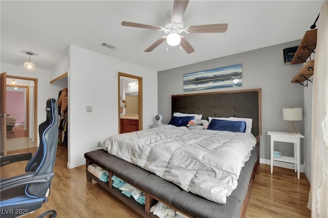 bedroom with ceiling fan, visible vents, light wood-type flooring, baseboards, and ensuite bathroom