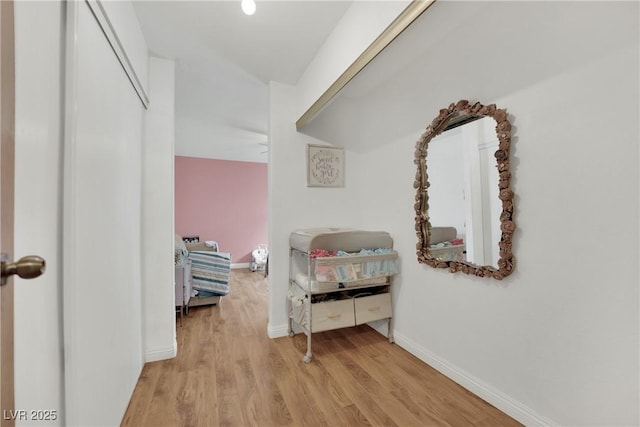 corridor with baseboards, wood finished floors, and vaulted ceiling