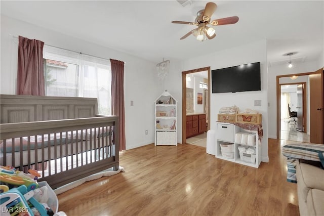 bedroom featuring baseboards, ensuite bath, and light wood-style flooring