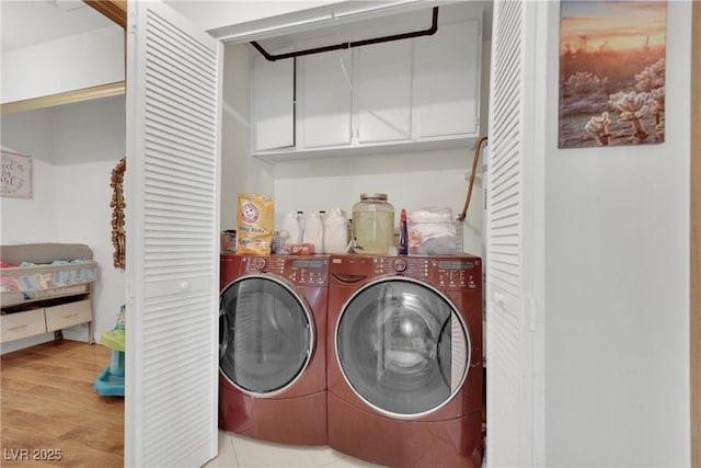 clothes washing area with wood finished floors, cabinet space, and washer and clothes dryer