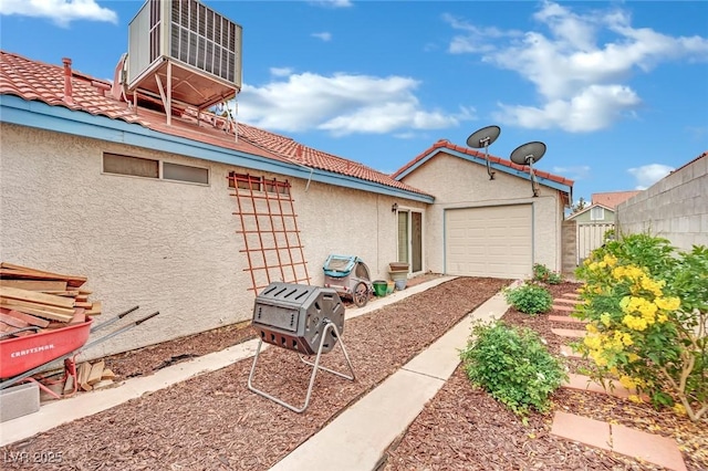 exterior space featuring a garage, stucco siding, and a tiled roof