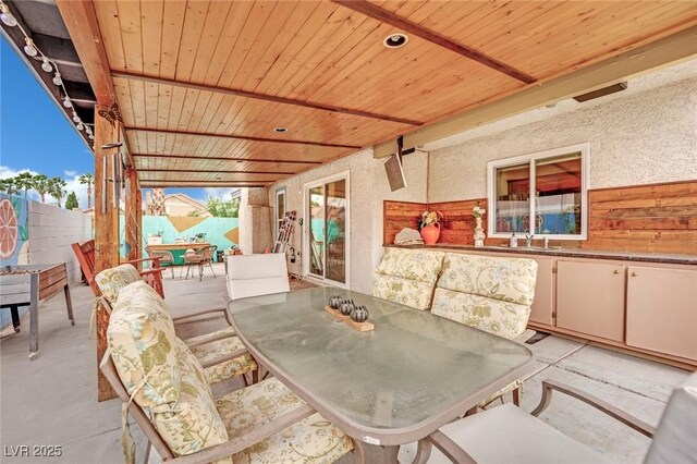 view of patio / terrace featuring a sink, fence, and outdoor dining area