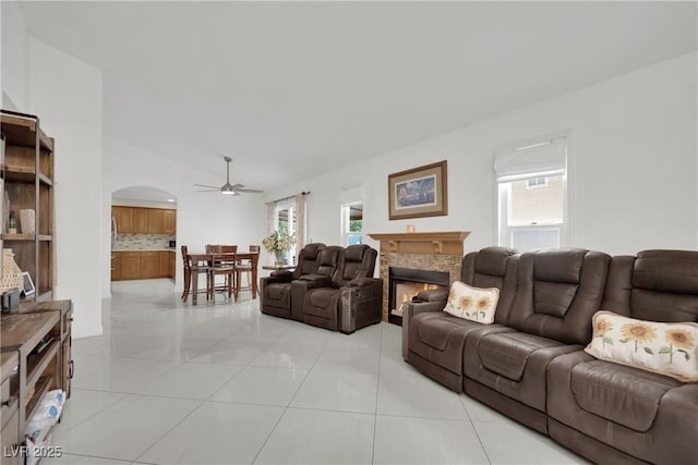 living room with arched walkways, ceiling fan, a healthy amount of sunlight, and vaulted ceiling