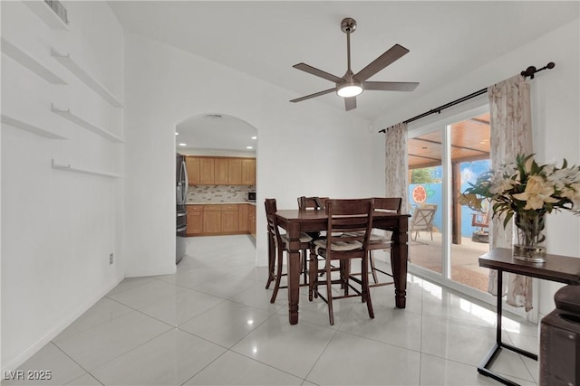 dining space with visible vents, a ceiling fan, light tile patterned flooring, baseboards, and arched walkways