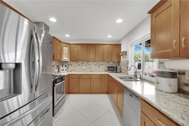 kitchen with light stone counters, a sink, appliances with stainless steel finishes, and tasteful backsplash