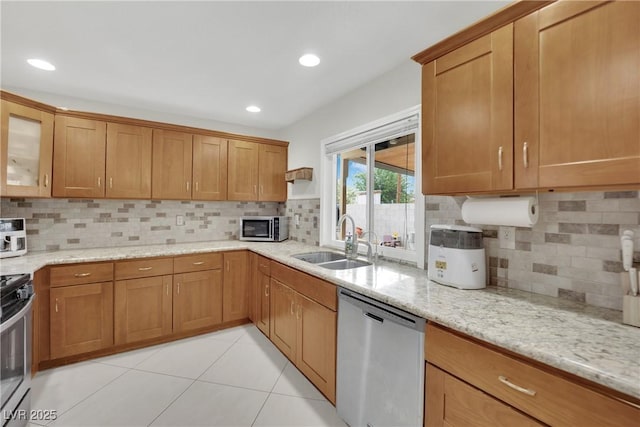kitchen with light stone counters, a sink, appliances with stainless steel finishes, and tasteful backsplash