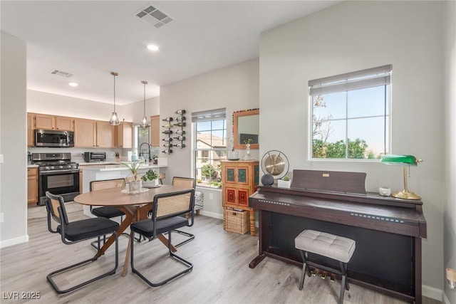 dining space featuring baseboards, light wood-style flooring, and visible vents