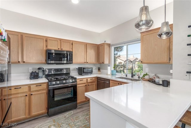 kitchen with a sink, appliances with stainless steel finishes, a peninsula, and light countertops