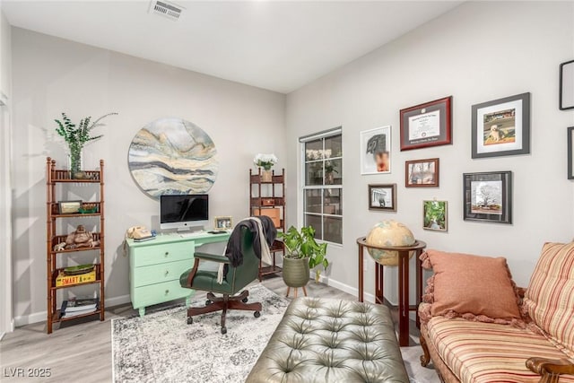 office area with baseboards, light wood finished floors, and visible vents