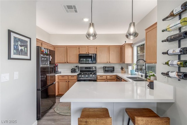 kitchen with visible vents, a peninsula, light countertops, a sink, and appliances with stainless steel finishes