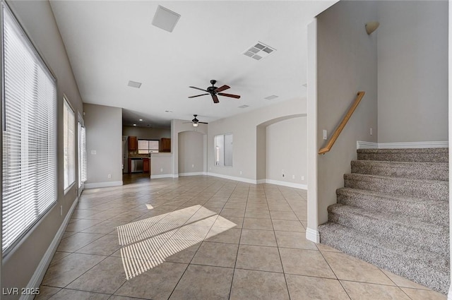 unfurnished living room with light tile patterned floors, ceiling fan, visible vents, and baseboards