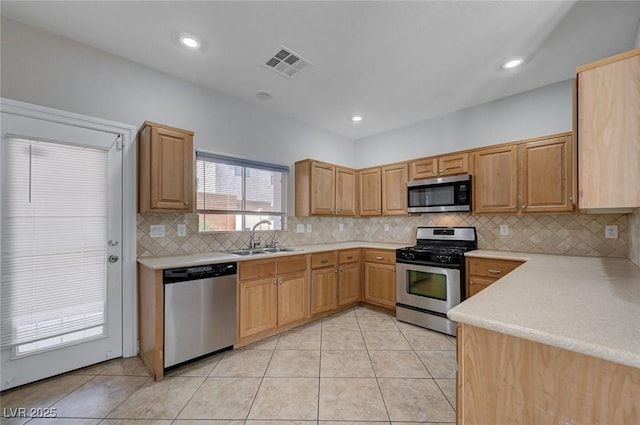 kitchen featuring visible vents, decorative backsplash, light countertops, a sink, and appliances with stainless steel finishes