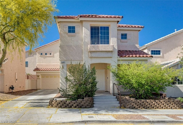 mediterranean / spanish home with an attached garage, stucco siding, driveway, and a tile roof