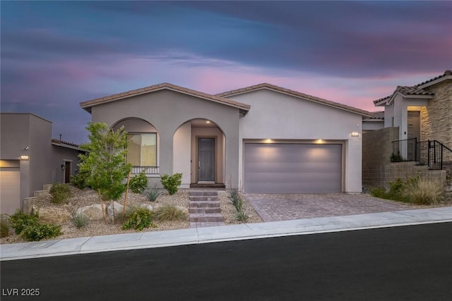 view of front facade featuring a tiled roof, a garage, driveway, and stucco siding
