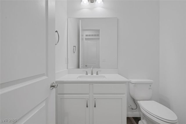 half bath featuring vanity and toilet