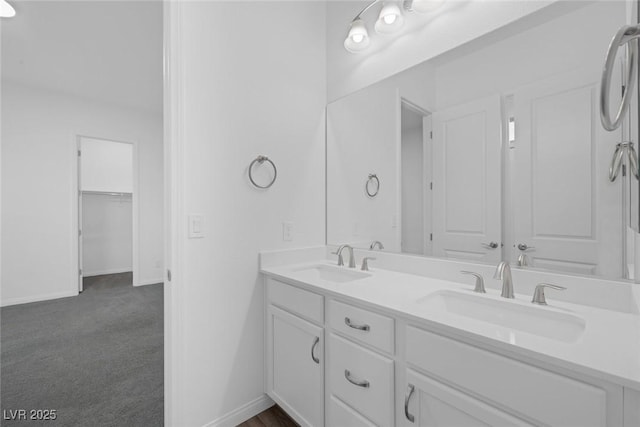 full bath with double vanity, a sink, and baseboards