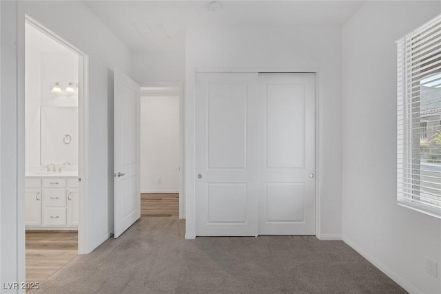unfurnished bedroom featuring carpet floors, ensuite bath, a sink, and a closet