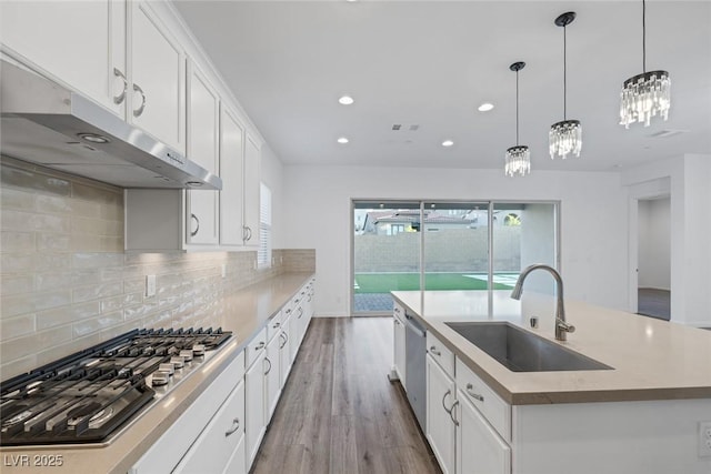 kitchen featuring an island with sink, recessed lighting, under cabinet range hood, a sink, and appliances with stainless steel finishes