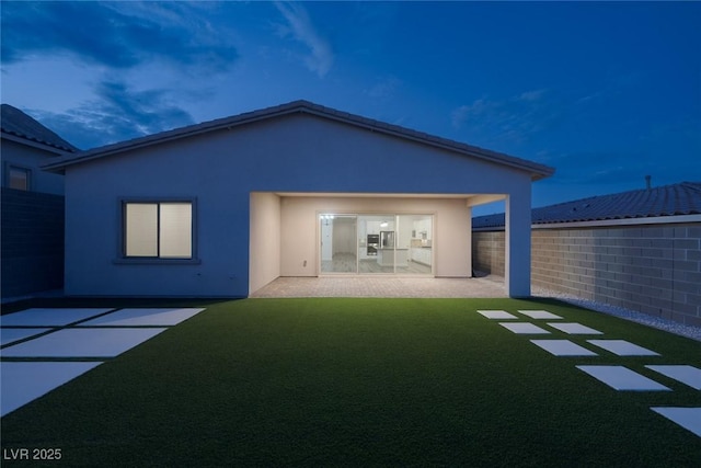 rear view of house featuring fence, a patio, stucco siding, and a yard