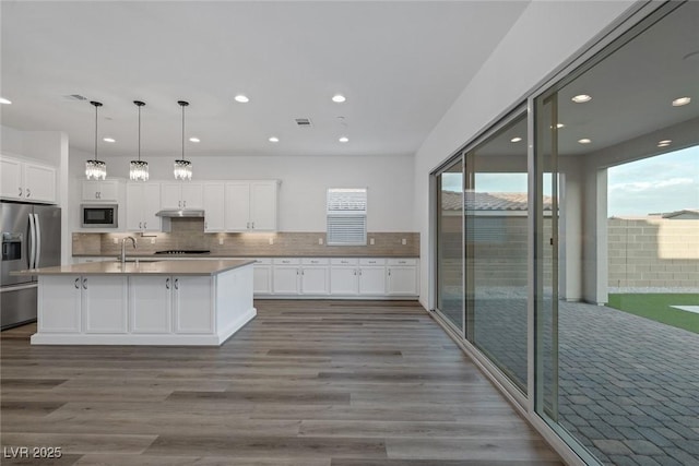 kitchen with a sink, stainless steel appliances, recessed lighting, and under cabinet range hood