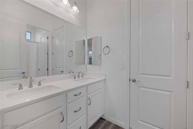 full bathroom with double vanity, a sink, and wood finished floors