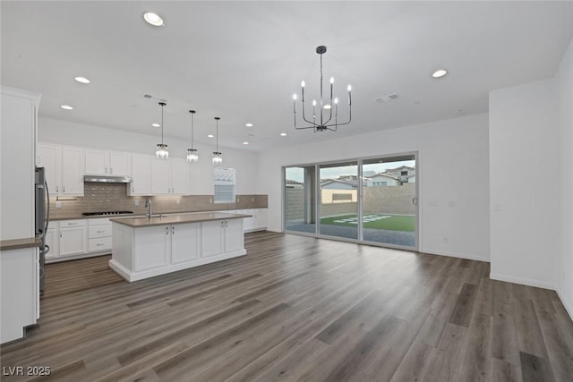 kitchen featuring under cabinet range hood, recessed lighting, open floor plan, and dark wood finished floors