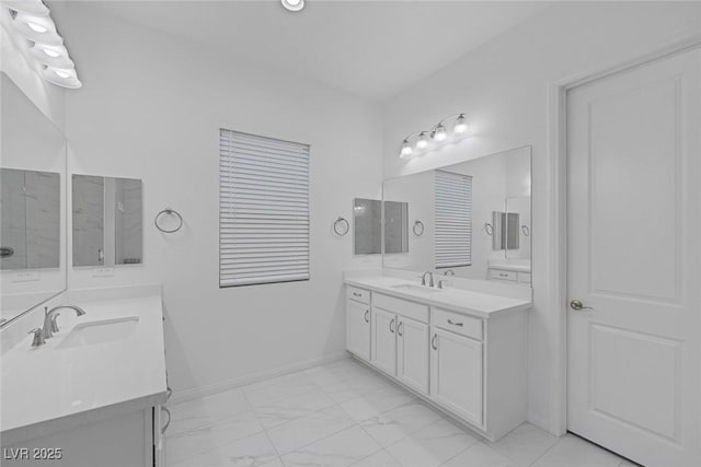 bathroom with a sink, baseboards, two vanities, and marble finish floor