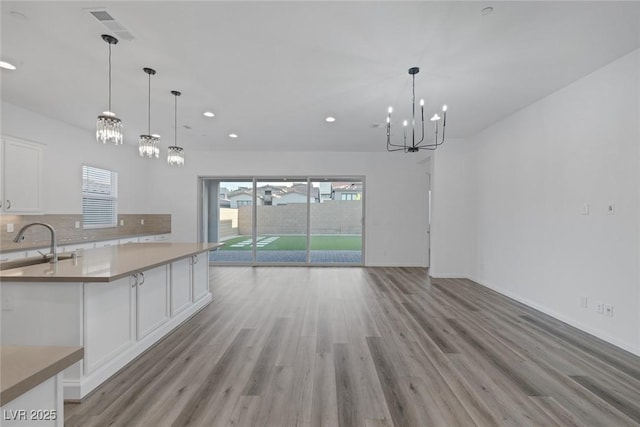 kitchen featuring white cabinetry, a notable chandelier, a sink, and light wood-style floors