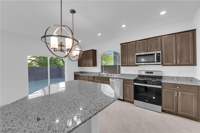 6142 Kelson Creek Ct, Las Vegas, NV 89118 - kitchen featuring an inviting chandelier, dark brown cabinetry, light stone countertops, a sink, and appliances with stainless steel finishes