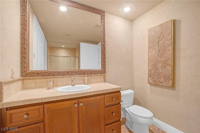 full bath with vanity, baseboards, a shower with shower door, and toilet