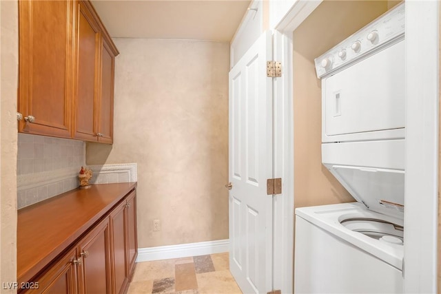 washroom with baseboards, stacked washer and clothes dryer, and laundry area