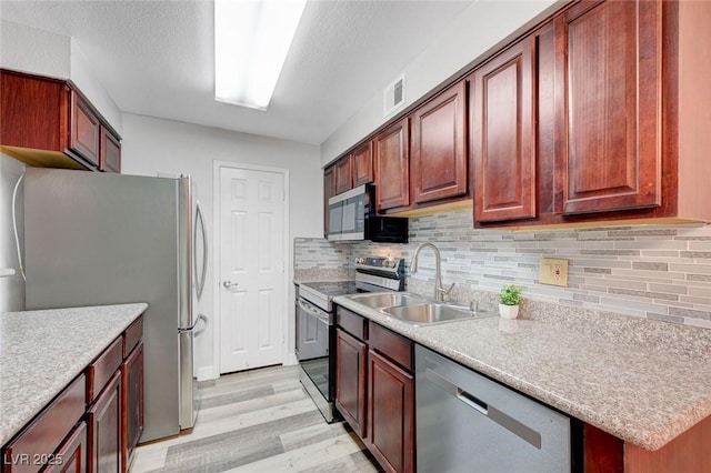 2451 N Rainbow Blvd Unit 2144, Las Vegas, NV 89108 - kitchen with appliances with stainless steel finishes, a sink, light wood-style floors, and decorative backsplash