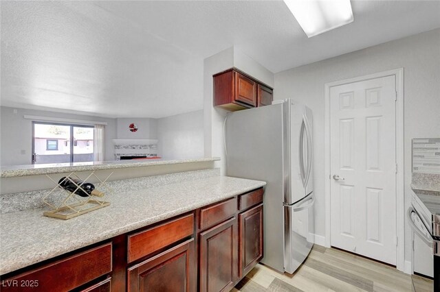 2451 N Rainbow Blvd Unit 2144, Las Vegas, NV 89108 - kitchen with freestanding refrigerator, light countertops, light wood-style floors, a fireplace, and dark brown cabinets