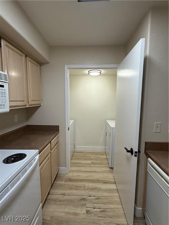 kitchen featuring dark countertops, light wood finished floors, washing machine and dryer, and white appliances