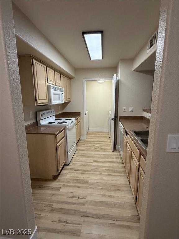 kitchen featuring visible vents, white appliances, baseboards, light wood-type flooring, and a sink