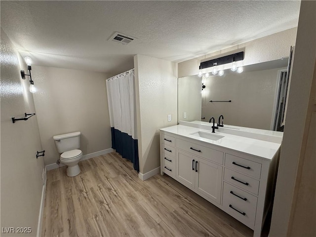full bath featuring visible vents, vanity, wood finished floors, toilet, and a textured ceiling