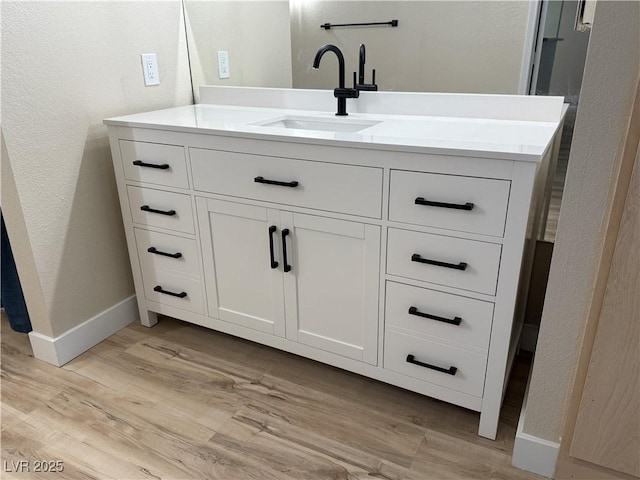 bathroom featuring vanity, baseboards, a textured wall, and wood finished floors