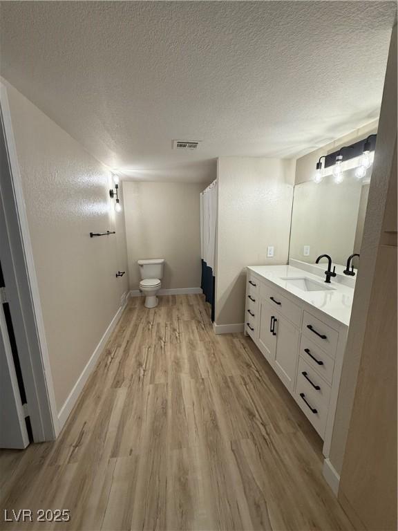 bathroom featuring wood finished floors, toilet, a textured ceiling, and visible vents
